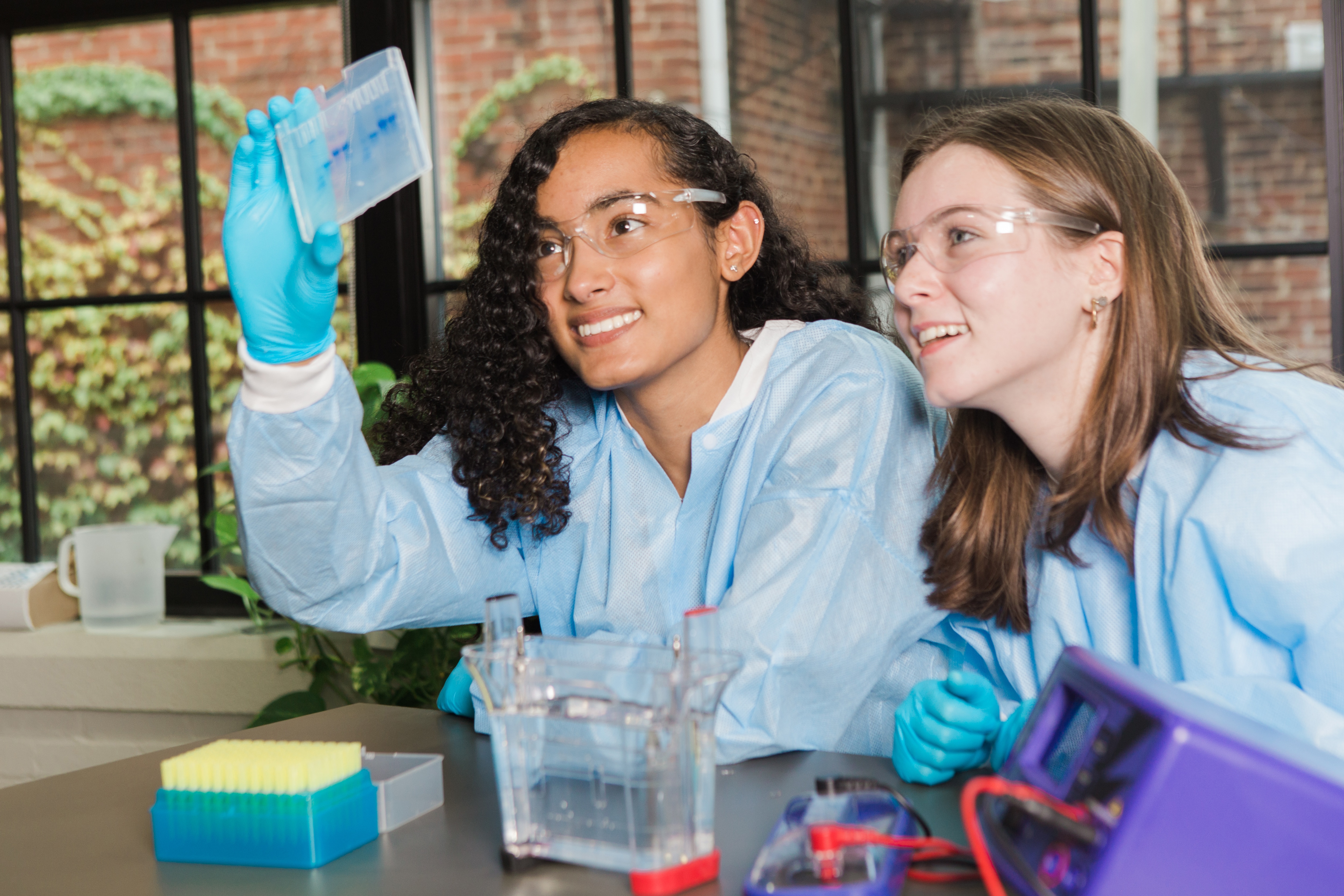 female students holding up a protein electrophoresis gel